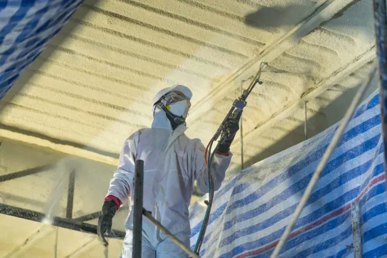 Technician spraying foam insulation on a garage ceiling in Long Island, NY.