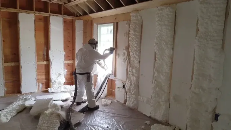 Technician applying spray foam insulation to interior walls in Huntington, NY