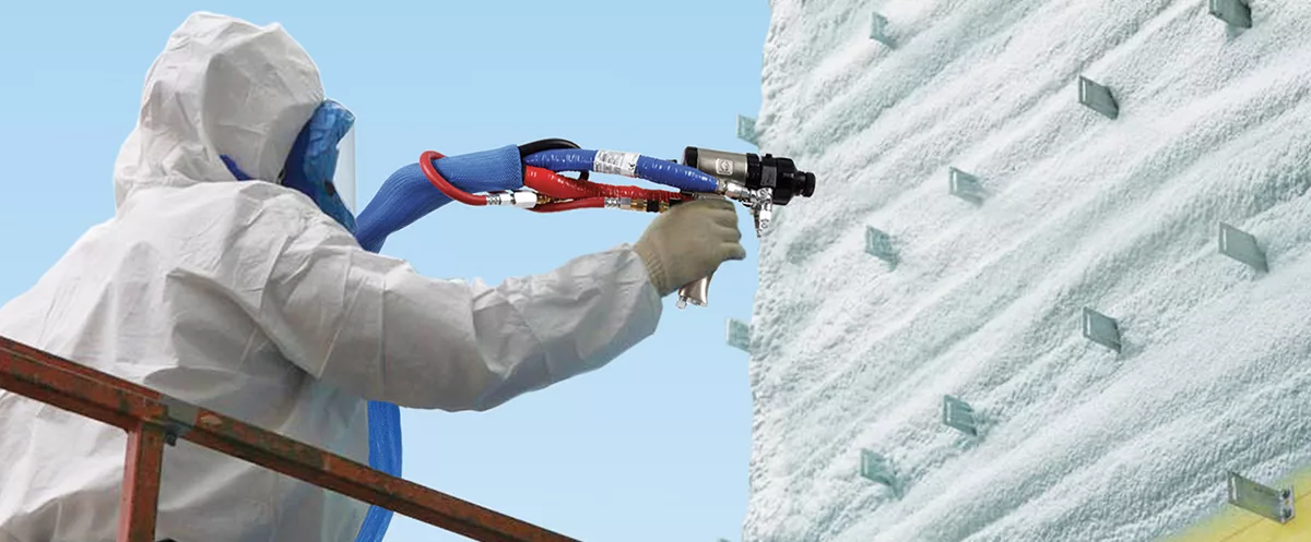 Technician applying spray foam insulation to the exterior wall of a Long Island building